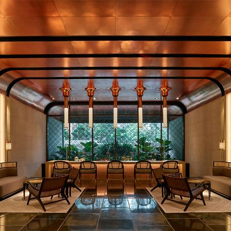 The Ruma Hotel And Residences Kuala Lumpur Eksteriør billede The image shows a stylish interior space with a modern and elegant design. The walls have a sleek, warm-toned finish, and there are large windows that provide natural light. The ceiling features striking architectural lines, likely in a metallic mate