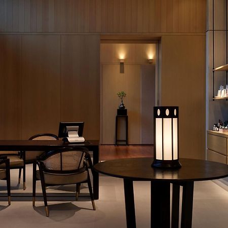 The Ruma Hotel And Residences Kuala Lumpur Eksteriør billede The photo shows a modern, minimalist interior space. It features a wooden wall with soft lighting, enhancing a calm atmosphere. In the foreground, there is a round table with a uniquely designed lamp on it. Surrounding the table, there are stylish wo
