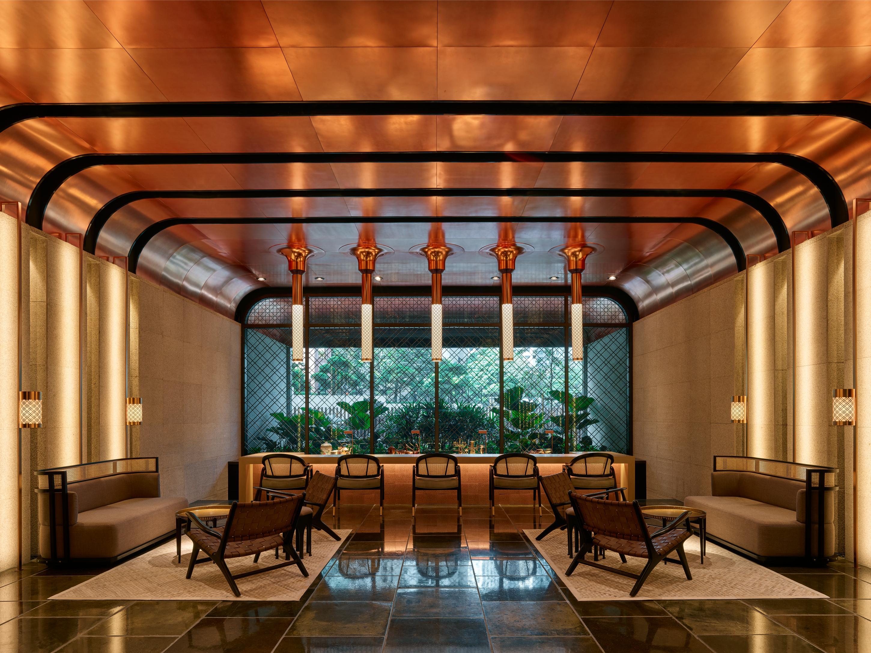 The Ruma Hotel And Residences Kuala Lumpur Eksteriør billede The image shows a stylish interior space with a modern and elegant design. The walls have a sleek, warm-toned finish, and there are large windows that provide natural light. The ceiling features striking architectural lines, likely in a metallic mate