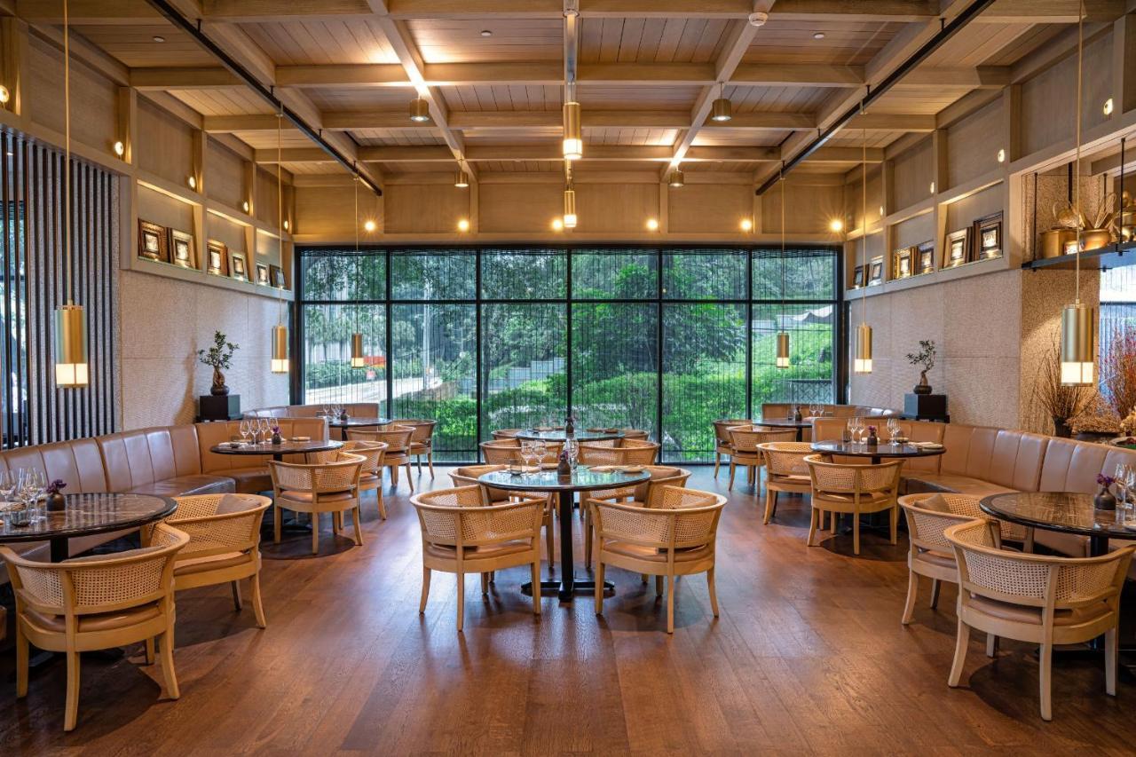 The Ruma Hotel And Residences Kuala Lumpur Eksteriør billede The photo shows the interior of a modern restaurant. It features wooden flooring, large windows that let in natural light, and an open layout. The seating consists of round tables surrounded by chairs, along with some cushioned booths. The decor has 